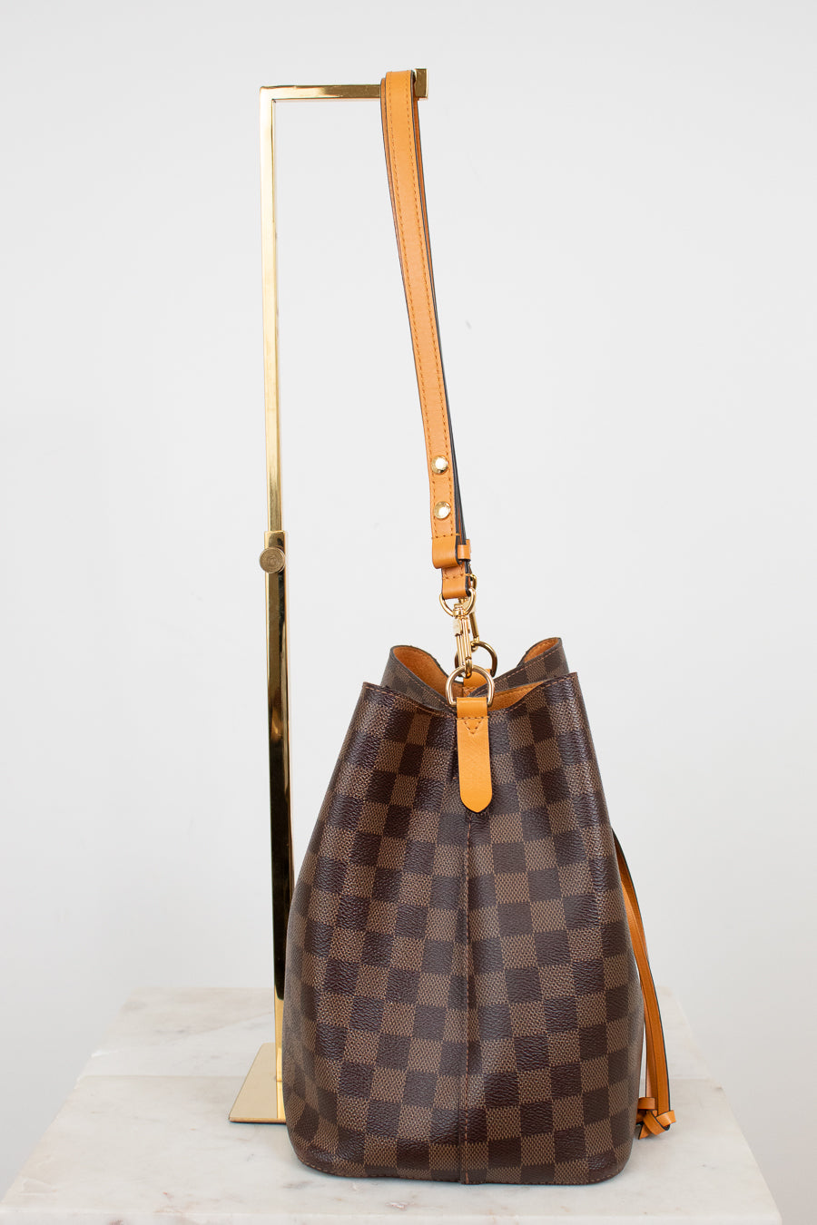 Brown checkered handbag with orange handle on a white background