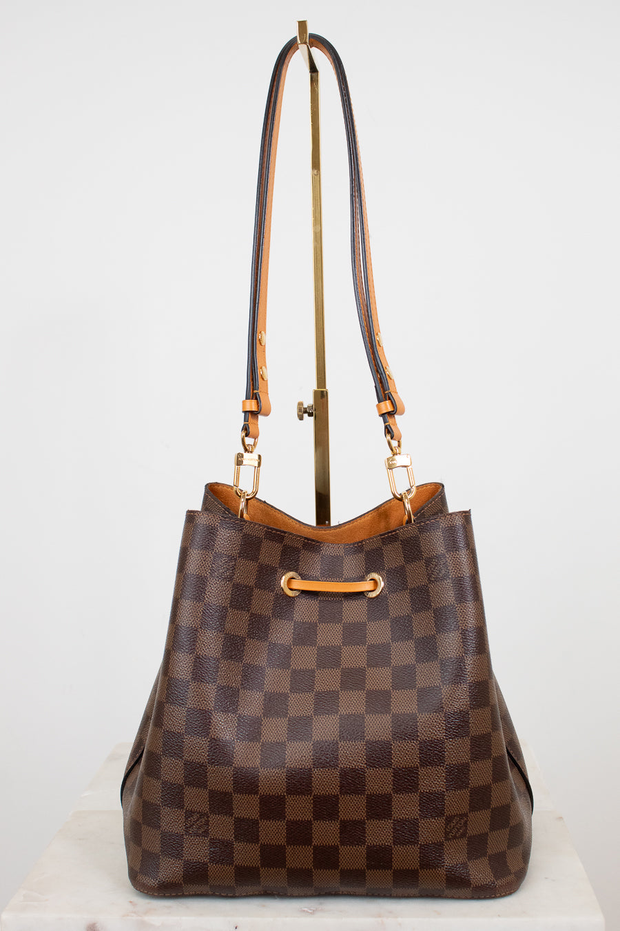 Brown checkered handbag with gold and orange accents on a white background
