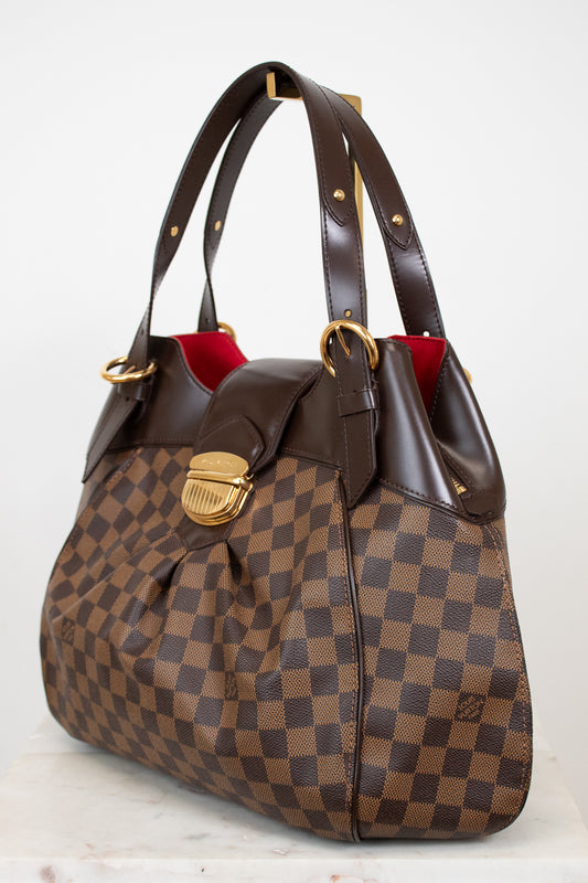 Brown checkered handbag with gold accents on a white background