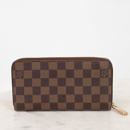 Brown checkered wallet on a white marble surface