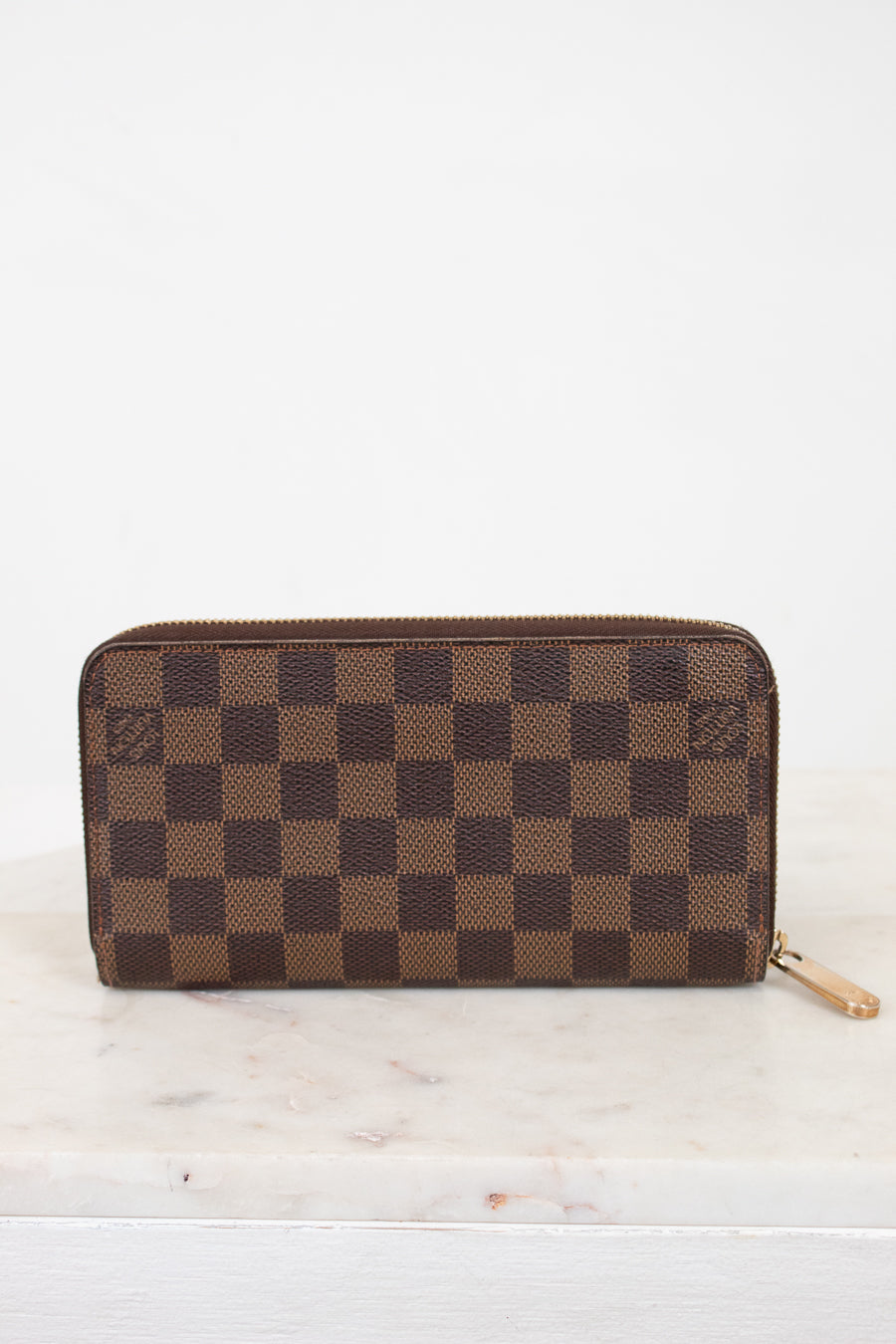 Brown checkered wallet on a white marble surface