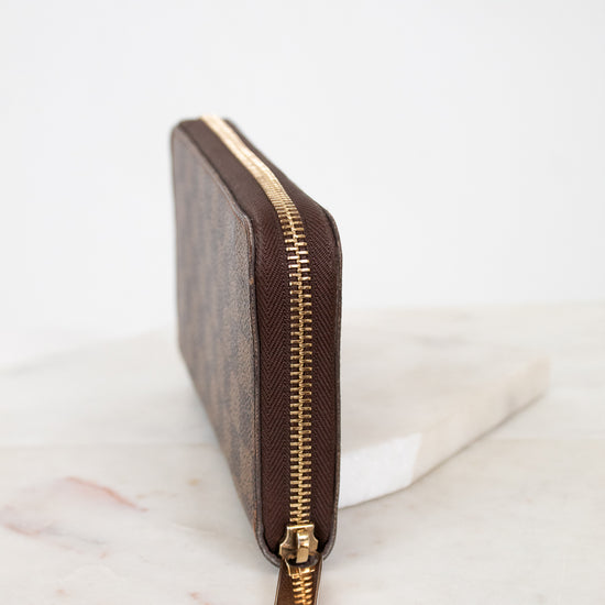 Brown wallet with gold zipper on a marble surface