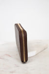 Brown wallet with gold zipper on a marble surface