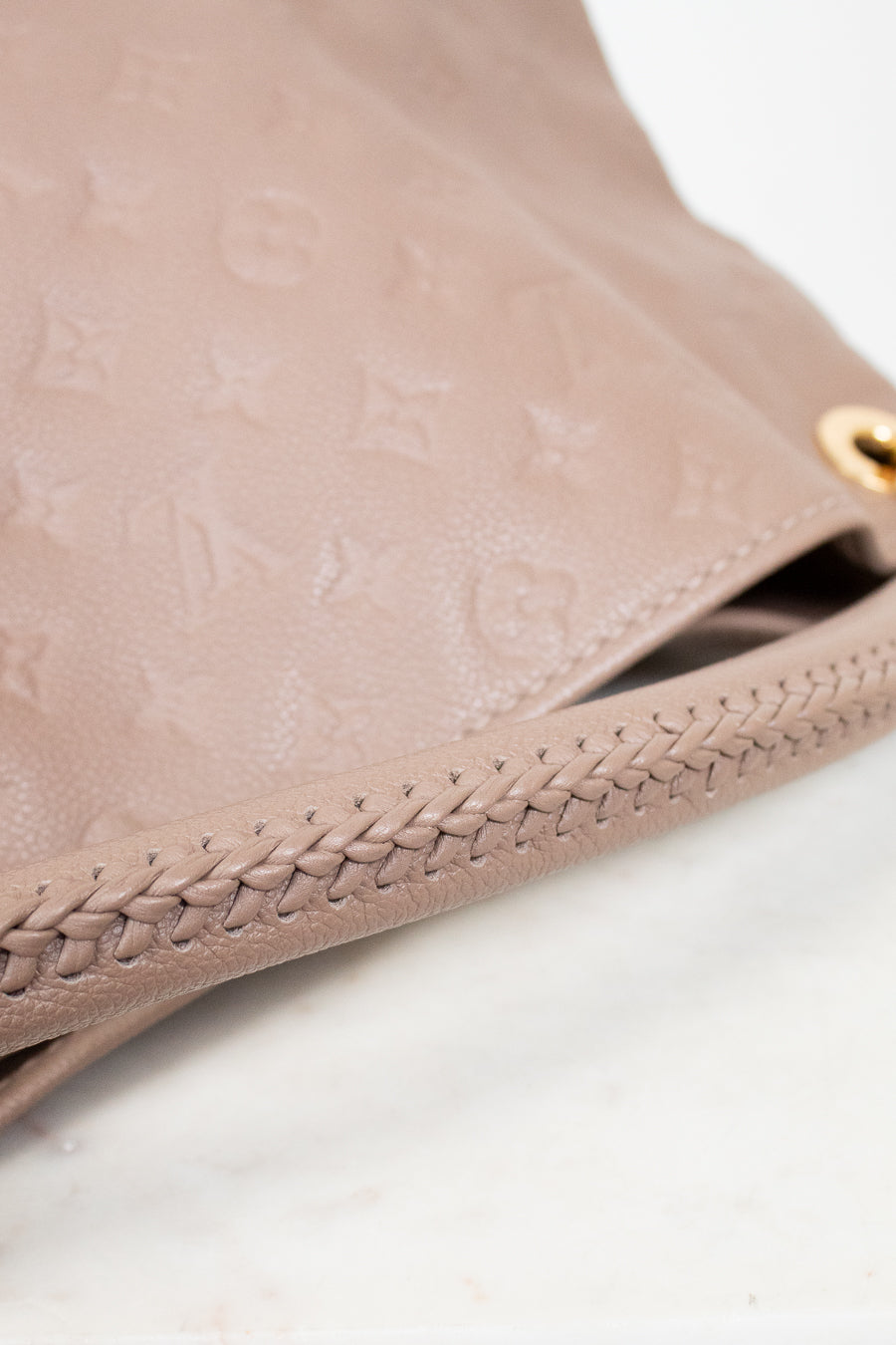 Close-up of a beige leather purse with braided edge on a white background