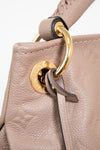 Close-up of a beige leather handbag with a gold clasp on a white background