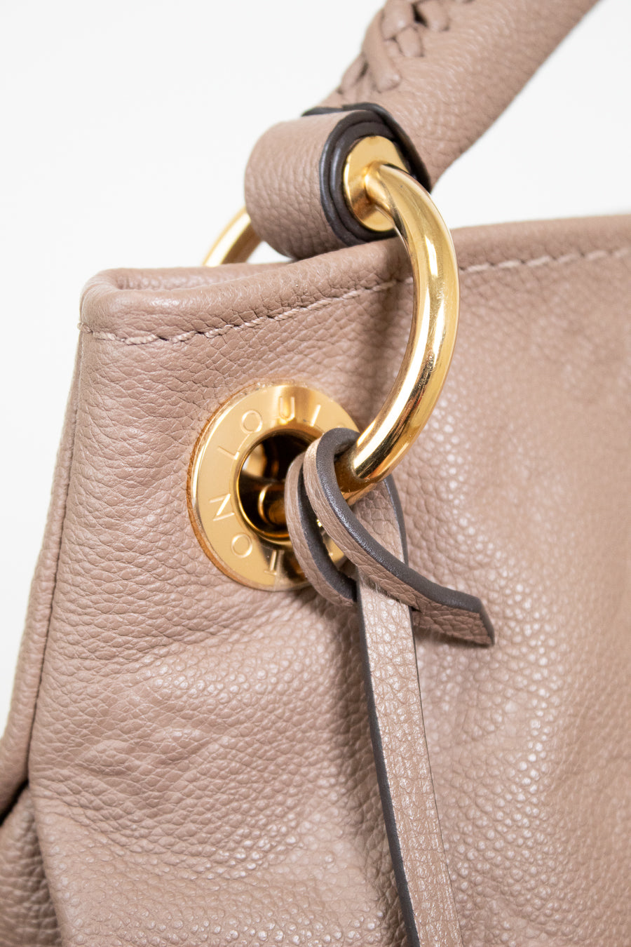 Close-up of a beige leather handbag with a gold clasp on a white background
