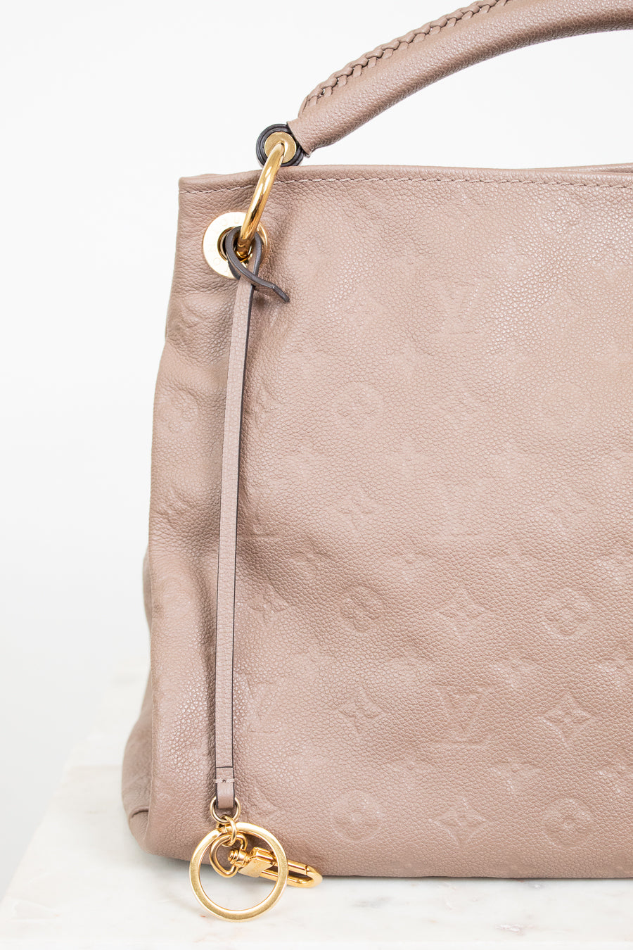 Beige handbag with gold hardware on a white background