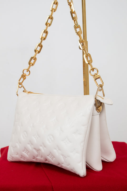 White handbag with gold chain strap on a red surface