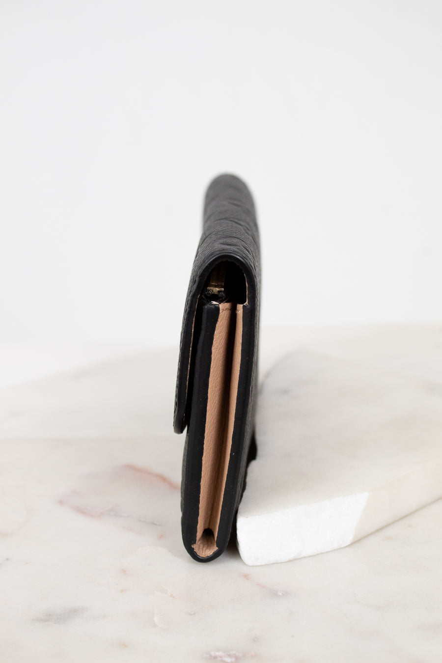 Black wallet on a white marble surface