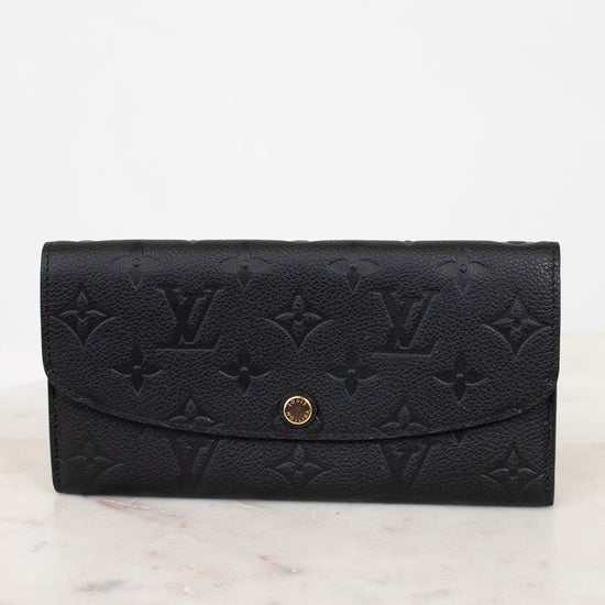 Black embossed wallet with gold clasp on a white marble surface