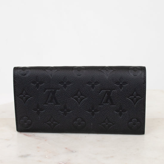 Black embossed wallet on a white marble surface