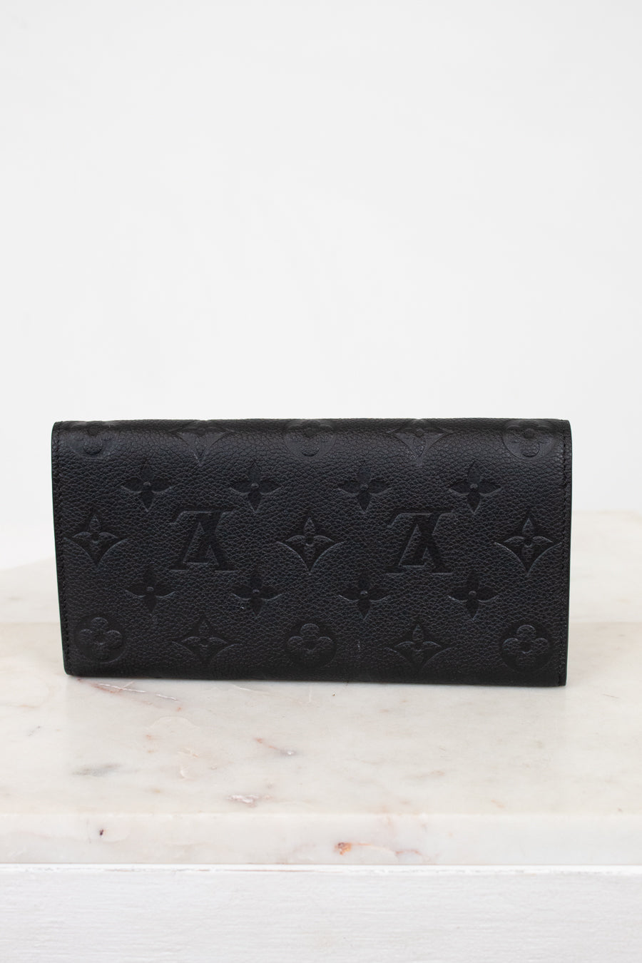 Black embossed wallet on a white marble surface