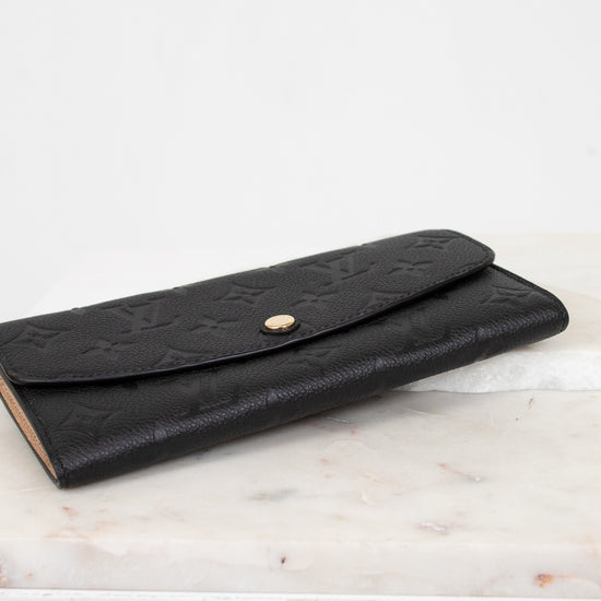 Black embossed wallet on a marble surface with a white background