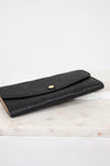 Black embossed wallet on a marble surface with a white background