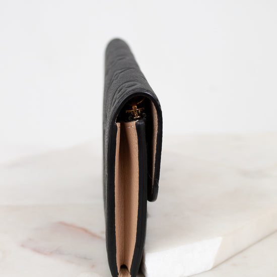 Black wallet with a brand logo on a white marble surface
