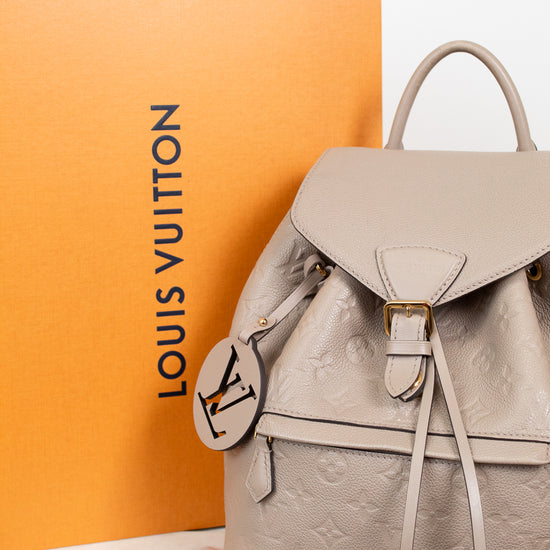 Louis Vuitton backpack with monogram pattern on a white surface with an orange Louis Vuitton box in the background.