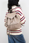 Person wearing a beige backpack with a white background