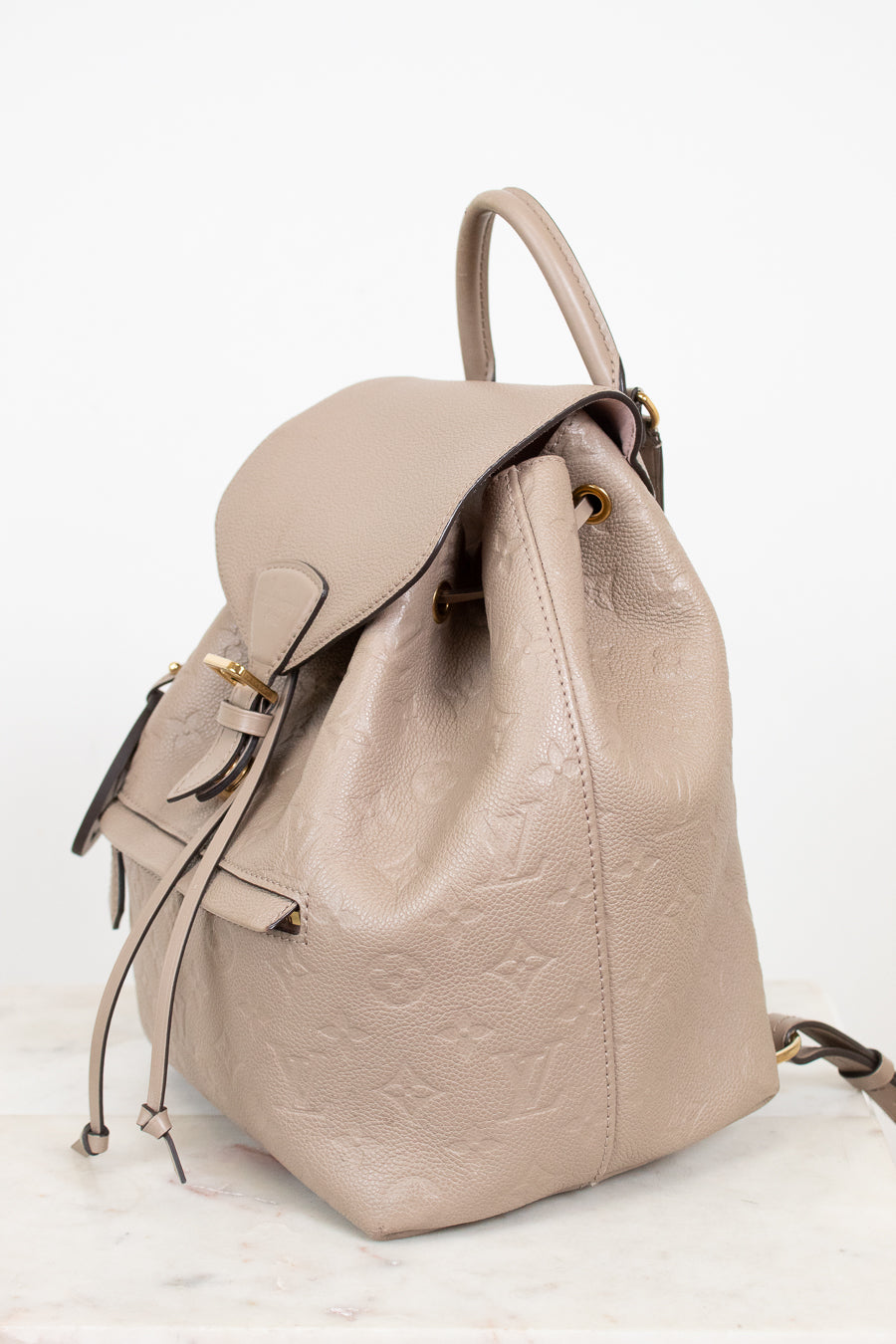 Beige backpack with a subtle logo pattern on a white background