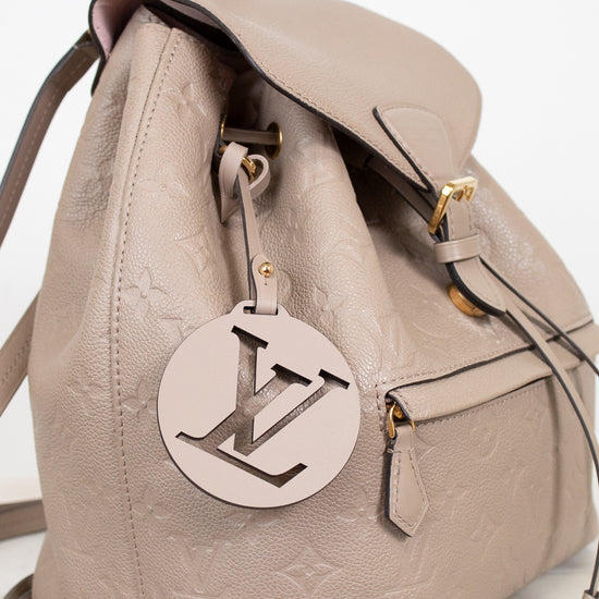 Beige backpack with a prominent logo tag on a light background