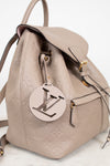 Beige backpack with a prominent logo tag on a light background