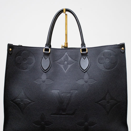 Black embossed handbag with gold accents on a white background