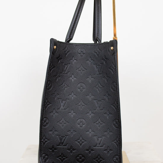 Black leather handbag with monogram pattern on a white background