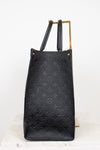 Black leather handbag with monogram pattern on a white background