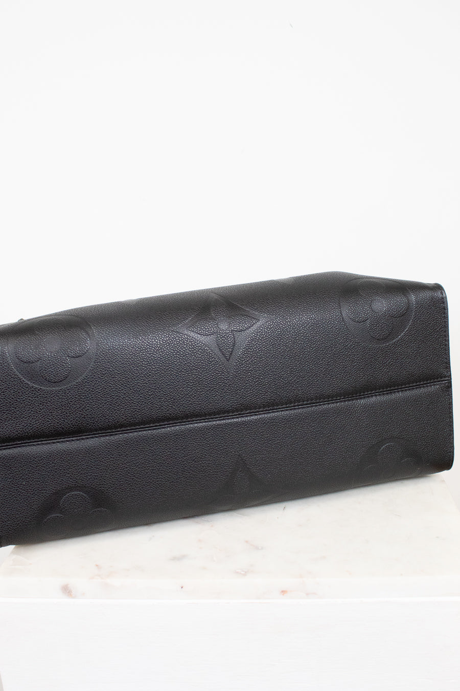Bottom view of black bag with embossed logo on a white background