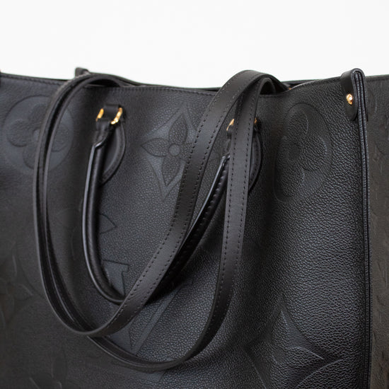 Black leather handbag with embossed design on a light gray background
