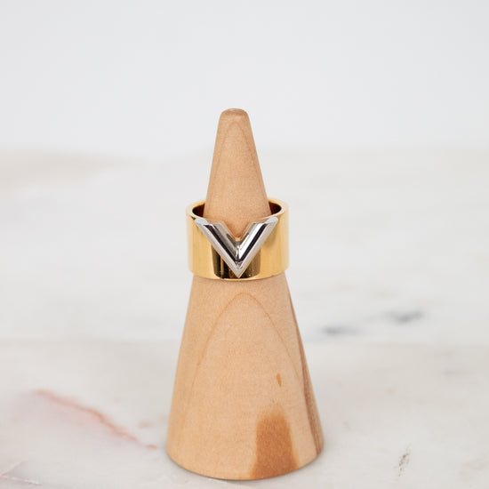 Gold and silver ring on a wooden ring stand sitting on a marble surface