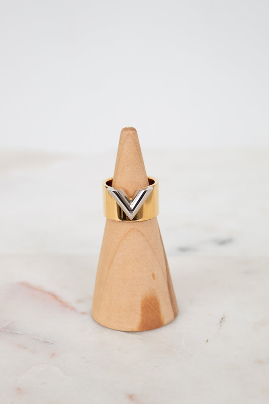 Gold and silver ring on a wooden ring stand sitting on a marble surface