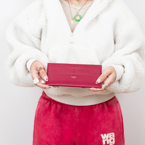 Person holding a red wallet with a plain background