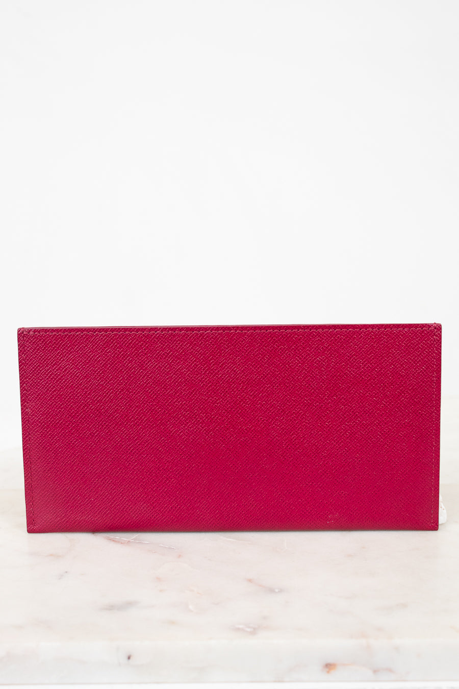 Pink wallet on a white marble surface