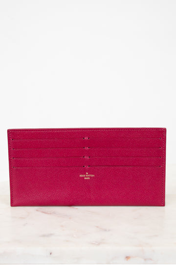 Pink wallet with brand logo on a light marble background