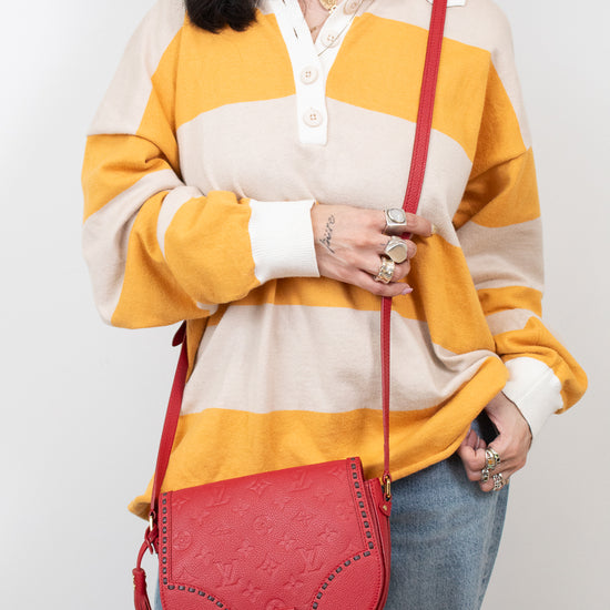Person wearing a yellow and beige striped sweater with a red handbag on a white background