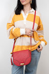 Person wearing a yellow and beige striped sweater with a red handbag on a white background