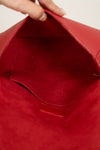 Close-up of a red bag with a hand opening it.