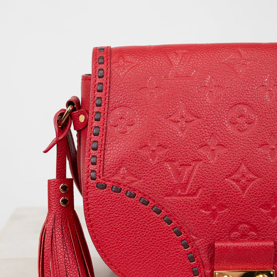 Red handbag with gold accents and a tassel on a light background