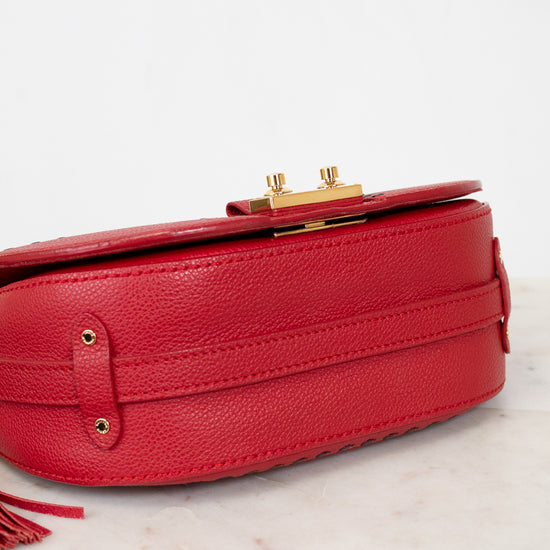 Red handbag with gold accents on a marble surface