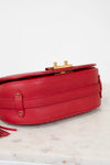 Red handbag with gold accents on a marble surface