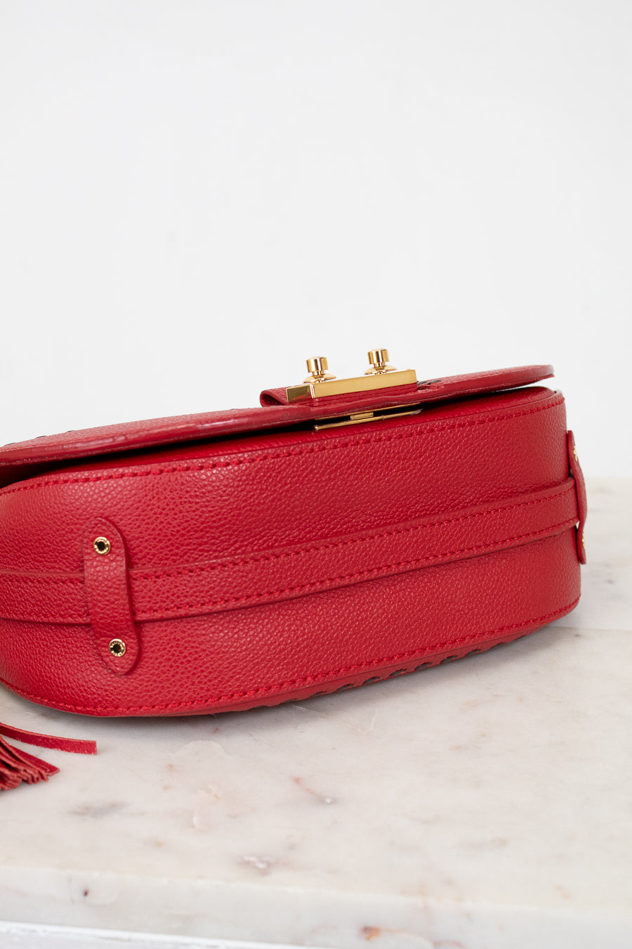 Red handbag with gold accents on a marble surface