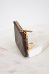 Small brown key pouch with gold chain on a white marble surface