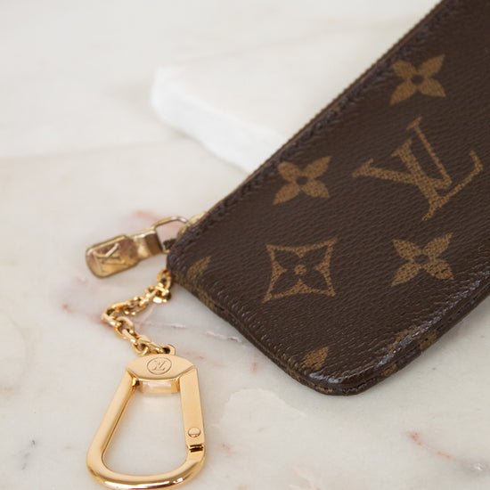 Louis Vuitton key pouch with gold chain on a marble surface