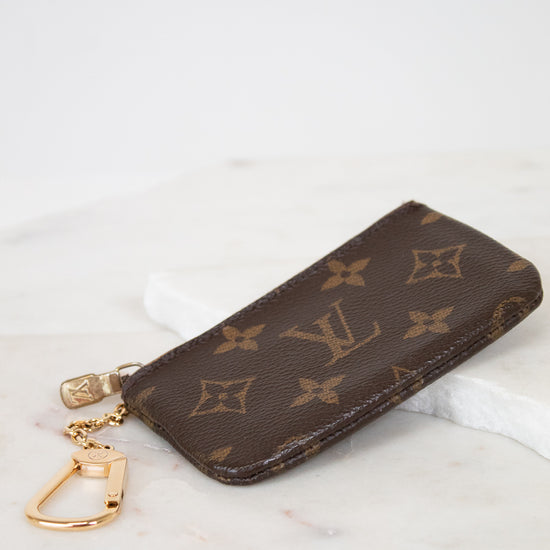 Louis Vuitton key pouch with monogram pattern on a marble surface