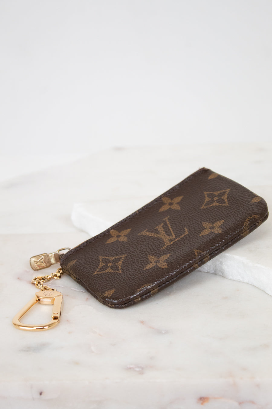 Louis Vuitton key pouch with monogram pattern on a marble surface