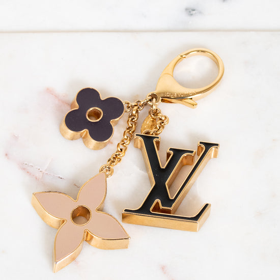 Louis Vuitton keychain with floral and monogram charms on a marble background