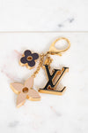 Louis Vuitton keychain with floral and monogram charms on a marble background
