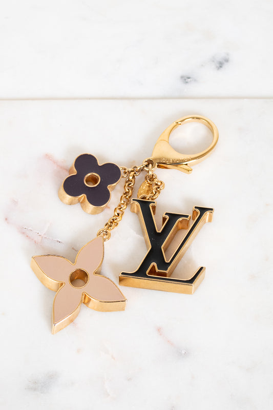 Louis Vuitton keychain with floral and monogram charms on a marble background