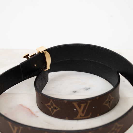 Black and brown Louis Vuitton belt showing black interior side on a marble surface