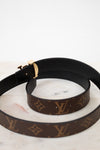 Black and brown Louis Vuitton belt showing black interior side on a marble surface